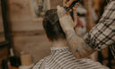 A barber cutting a guys hair.