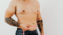 Man with a dad bod measuring his waist