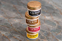 Layrite's Cement Clay, Superhold Pomade, Supershine Cream, and Original Pomade stacked on a counter.