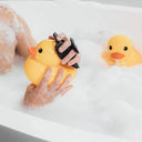 Person holding a yellow rubber duck with a camera lens in a bathtub