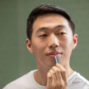 Man holding a small electronic device against a plain background
