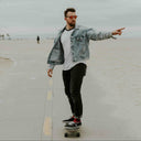Man skateboarding on a boardwalk with palm trees and a cloudy sky in the background