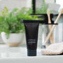 Black tube of CARDON sunscreen on a bathroom counter with plants and towels in the background