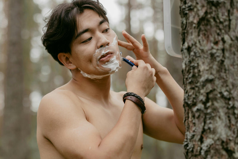 Man shaving at a campsite.