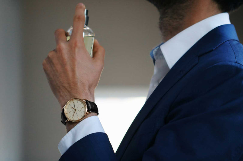 Person in a blue suit spraying perfume with a blurred background
